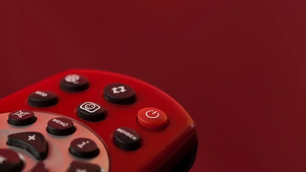 Hands holding a TV remote in front of a screen