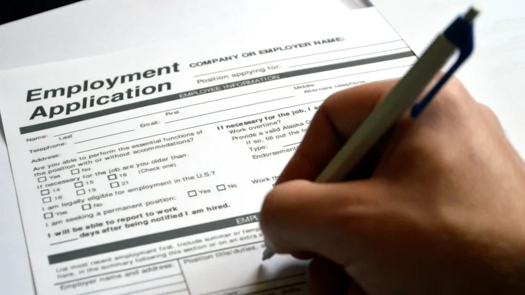 printed job application documents and a pen