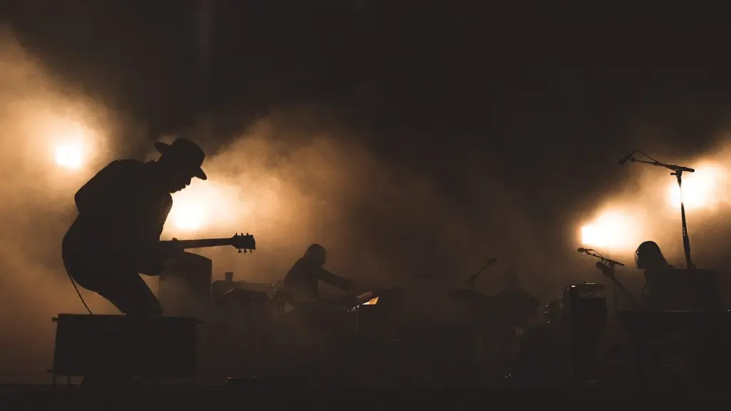 A dim stage with a microphone and audience silhouettes