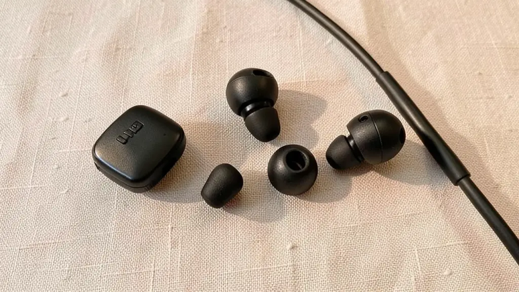 Close-up of inline remote and eartips with cable, on fabric background.