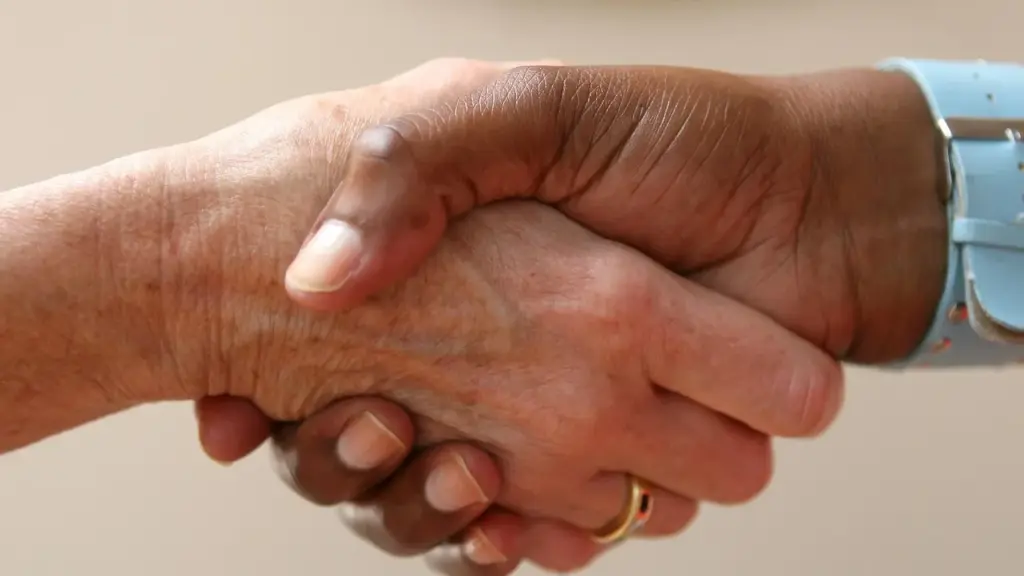 Two hands in a handshake over a table, symbolizing policy and business deals