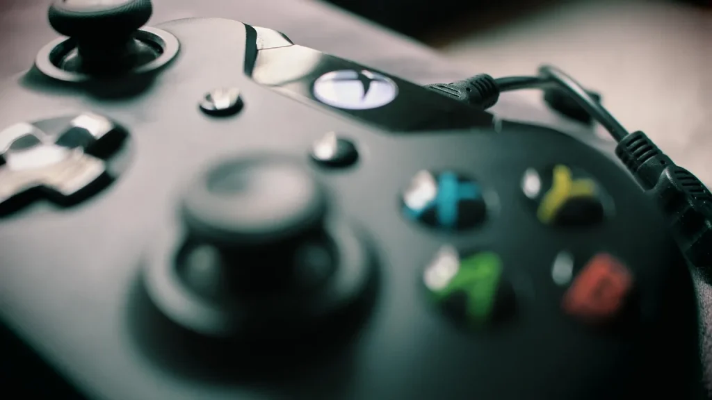 Hand holding a game controller in front of a TV showing a game
