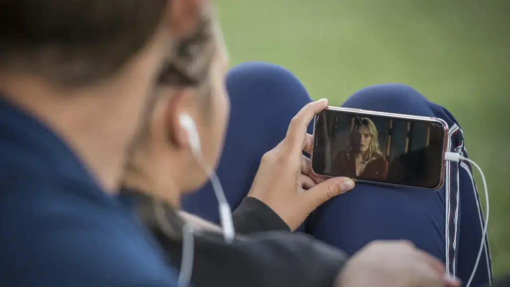 Hand holding a smartphone with a tablet or another device nearby
