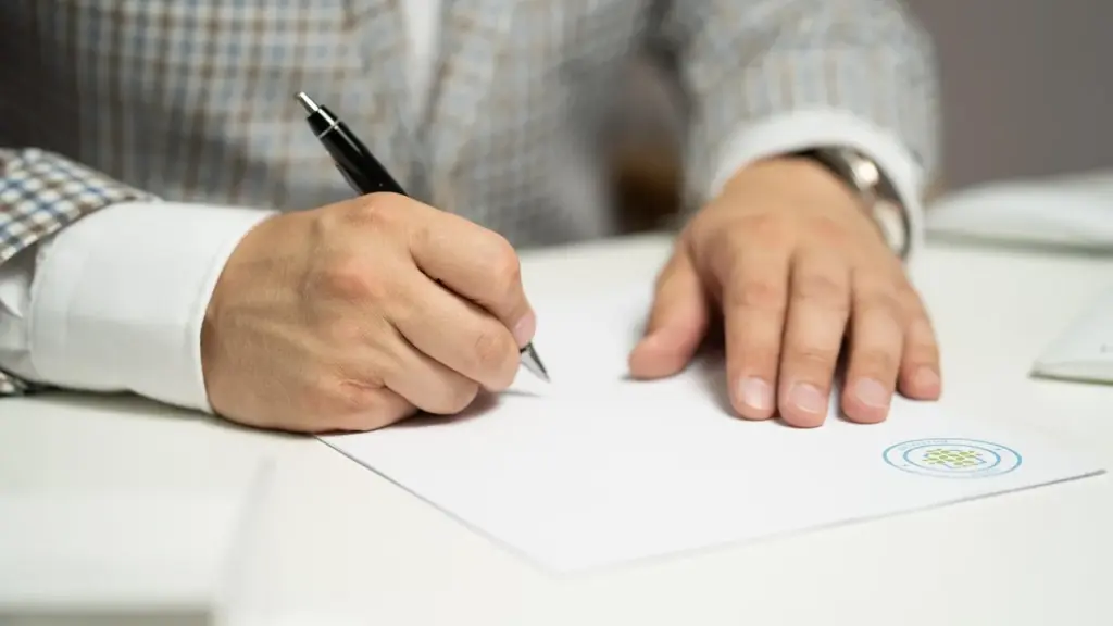 Hands holding a policy document with a pen ready to sign