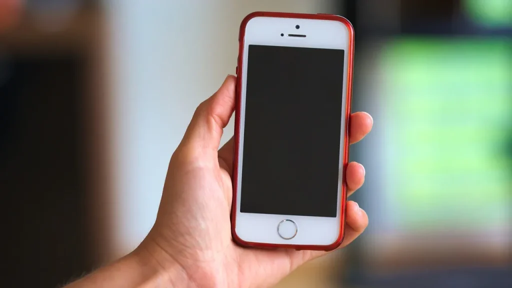 Person's hand holding a smartphone showing a game screen