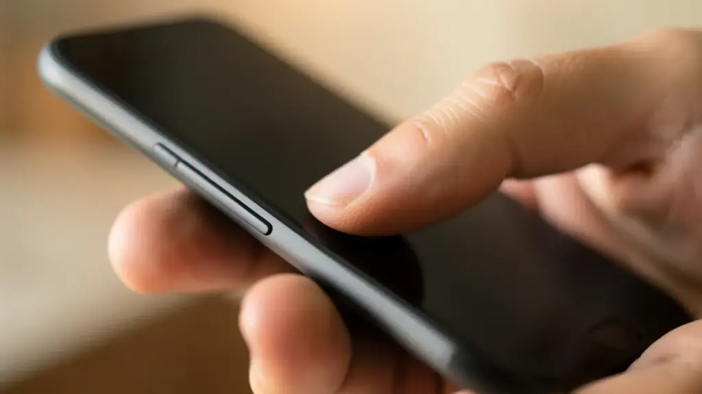 Thumb pressing the side button of a slim smartphone
