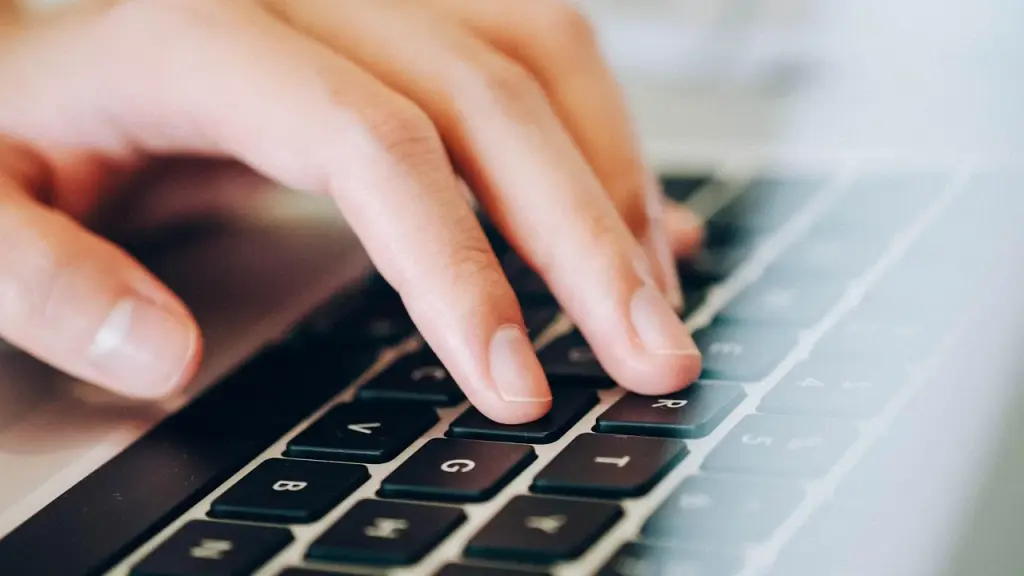 Hands typing on a keyboard with a coffee cup and monitor nearby