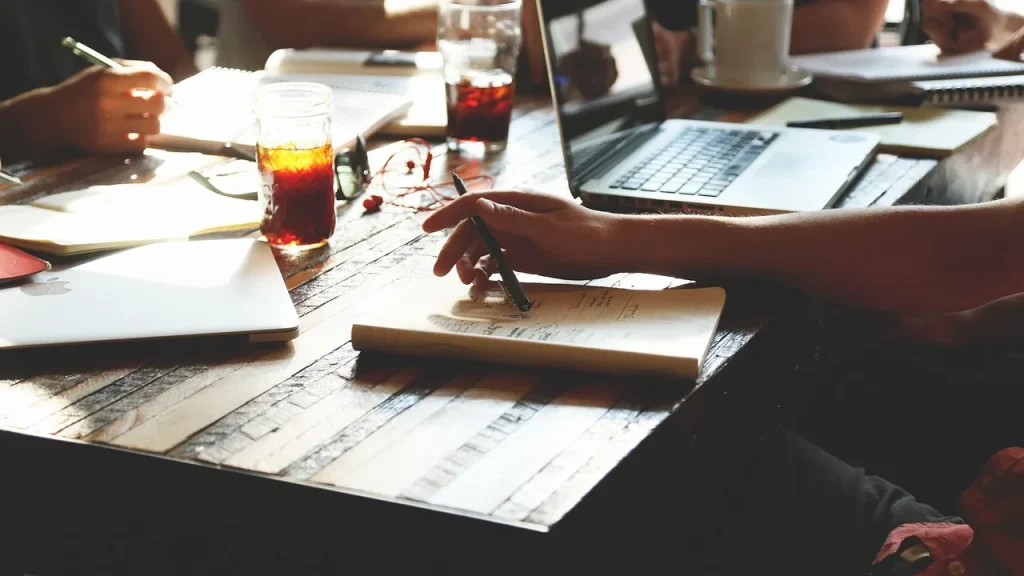 Team members around a table discussing AI project with laptops