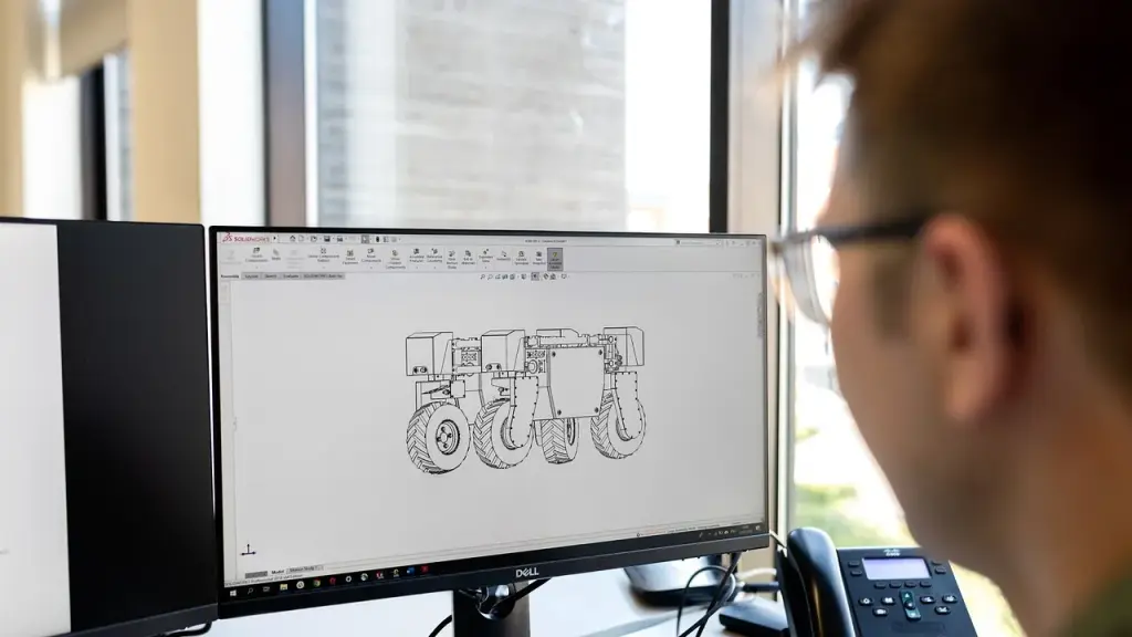 Person coding in a bright workspace with dual monitors