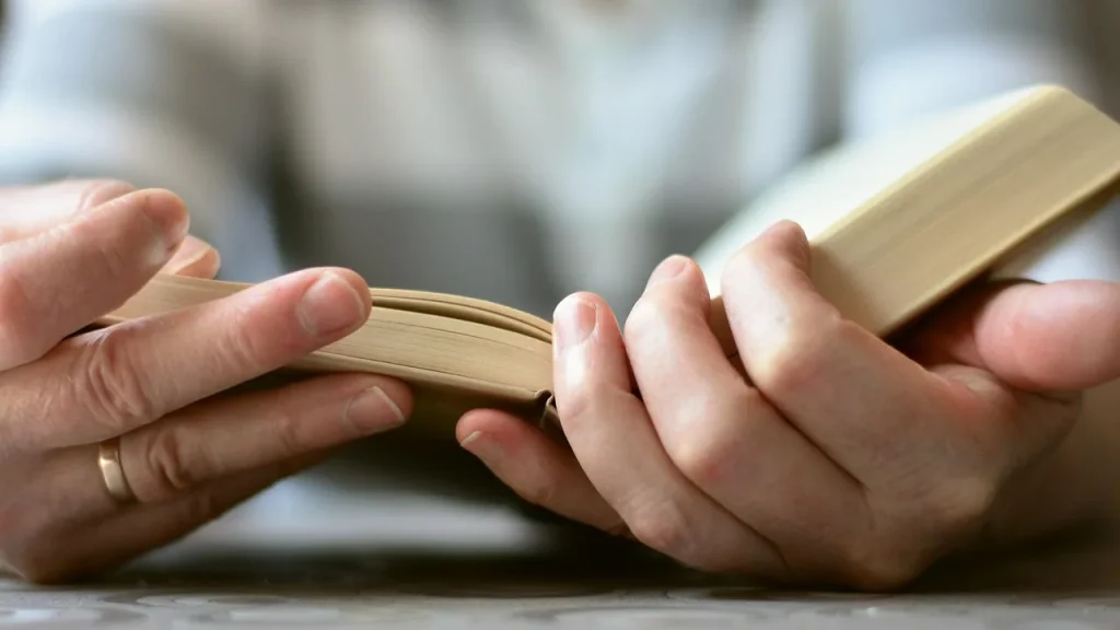 A hand holding a book in a dim room