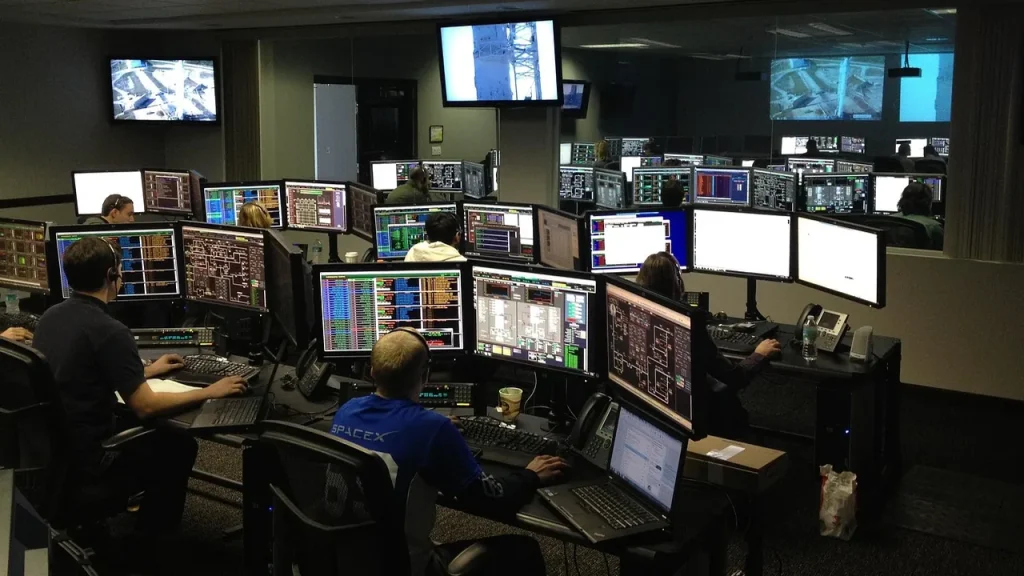 Mission control console with multiple screens tracking a satellite mission