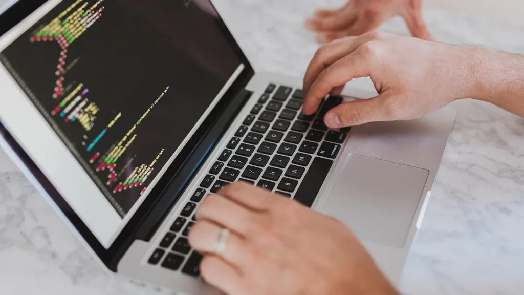 Hands typing code on a laptop with AI-assisted panels