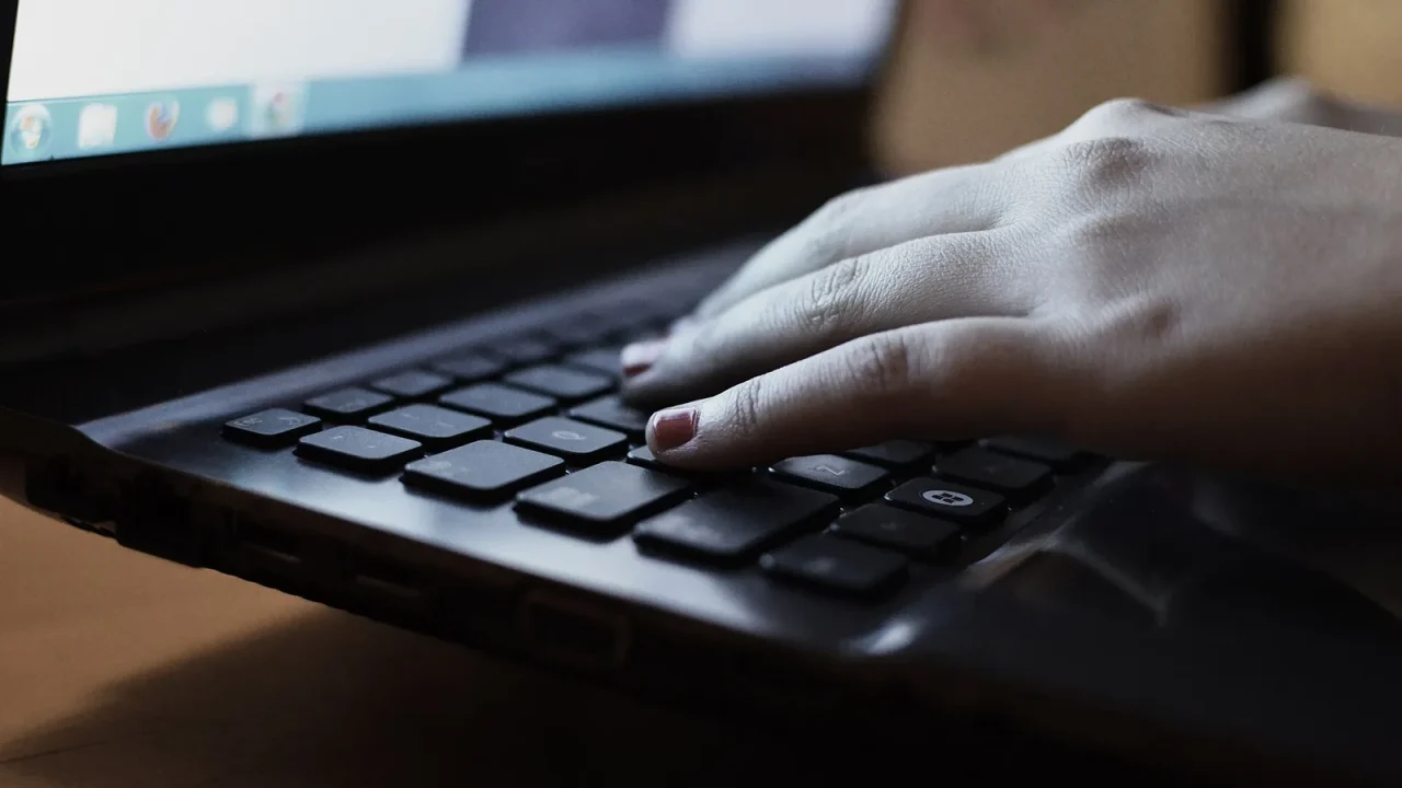Hands holding a tablet with headphones in the background