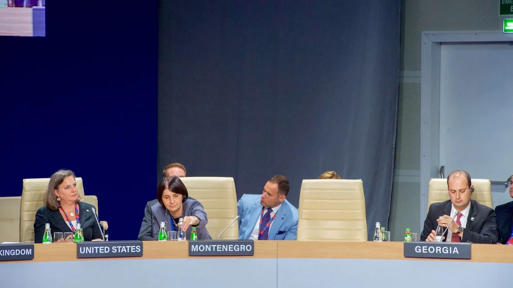 A conference room with a person speaking and a screen showing AI notes