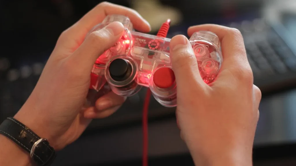 A person using a laptop with a game controller nearby, representing cross-device play