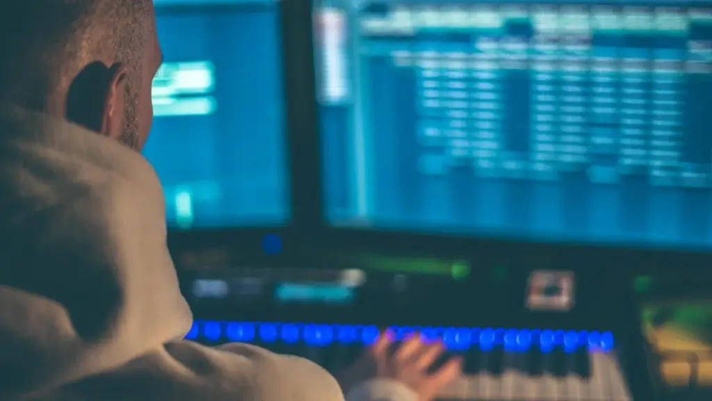 A music producer in a studio with a computer and audio gear, illustrating AI involvement
